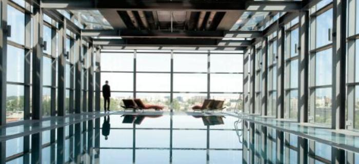 Szklana bryła basenu na ostatnim piętrze hotelu Andels z widokiem na rynek odrestaurowanej Manufakt